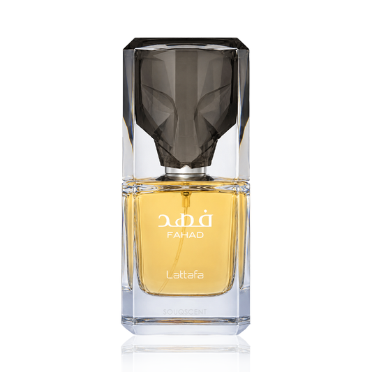 A faceted clear glass perfume bottle with a dark smoky cap and golden-yellow liquid inside, labeled 'FAHAD' and 'Lattafa', on a white background.